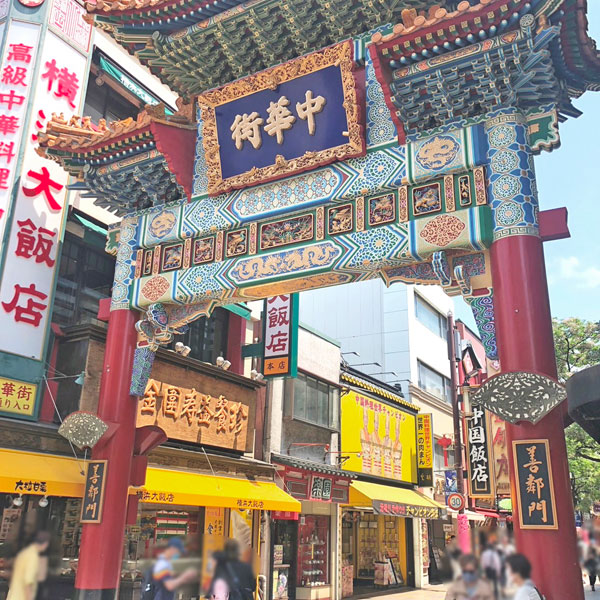 食べ物屋さんのビルに挟まれた善隣門の画像。大通りを多くの人が行きかっています